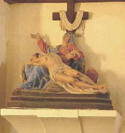 Dans la plupart des pietàs, la taille du Christ est réduite afin que son corps repose sur les genoux de la Vierge. Ici le Christ a une taille normale et seuls sa tête et son torse reposent sur les genoux de Marie
